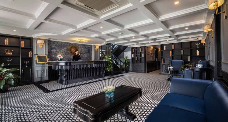 Hotelreceptie met een persoon aan de balie en elegante inrichting.