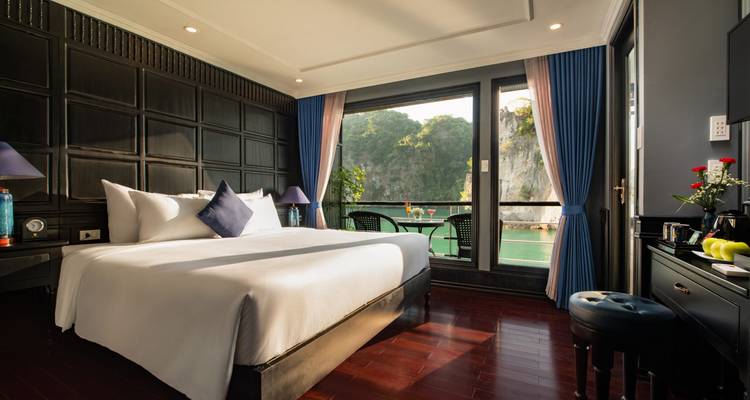 Luxe hotelkamer met een groot bed en raamzicht op water en kalkstenen kliffen.