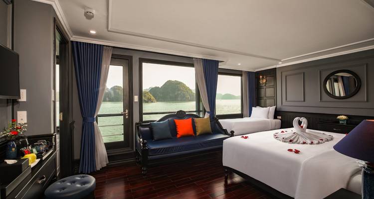 Ruime hotelkamer met uitzicht op de baai en decoratief opgemaakt bed.