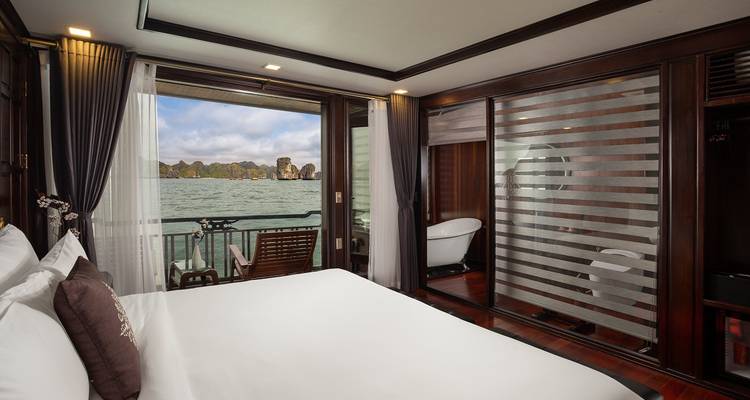 Chambre avec lit double et vue sur la baie et l'île par les fenêtres.