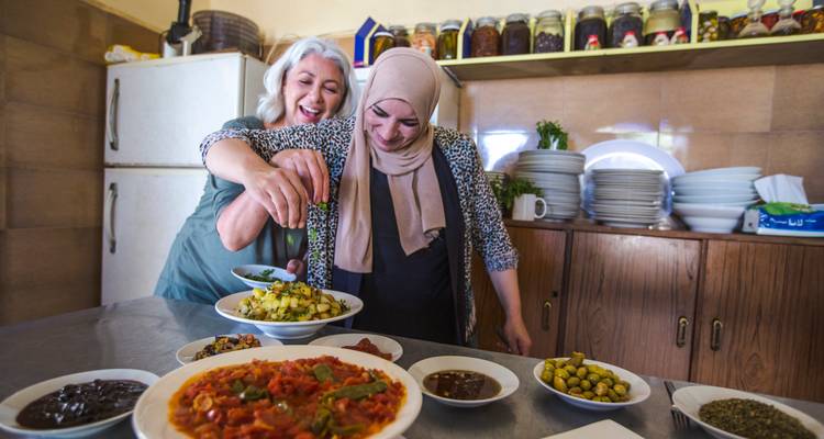 Deux femmes rient ensemble en préparant des plats locaux dans une cuisine de style maison