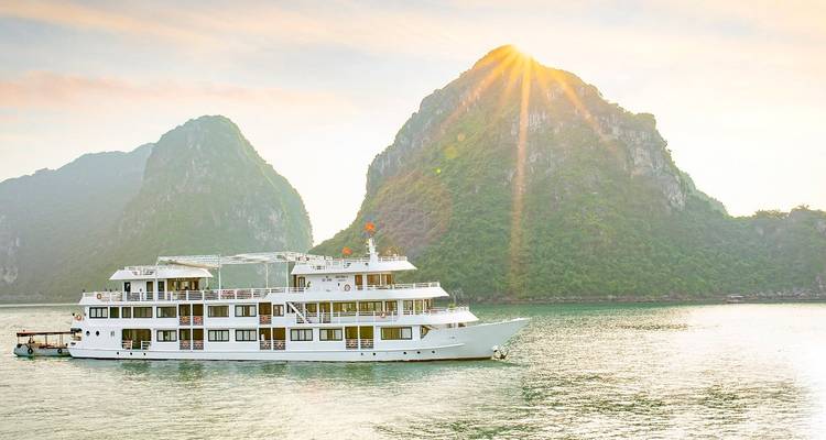 Cruise ship with limestone karst hills at sunset