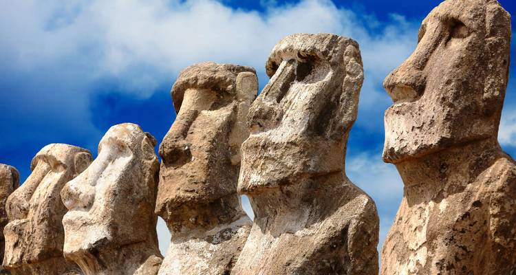 Close-up van Moai-beelden onder een blauwe lucht met witte wolken.
