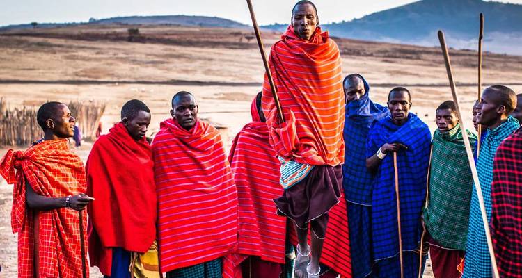 Gruppe von Menschen in bunter traditioneller Kleidung mit einer Person, die springt.