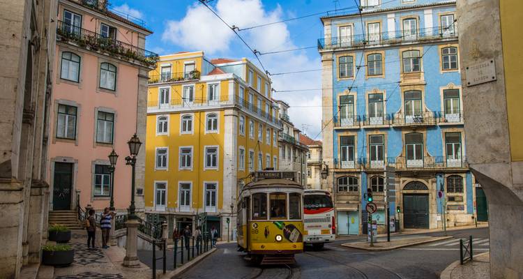 Classic yellow tram rattling through colorful streets of Lisbon’s historic center.