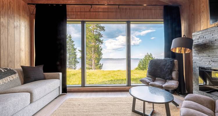 Interior of a cozy cabin with large windows facing a lake.