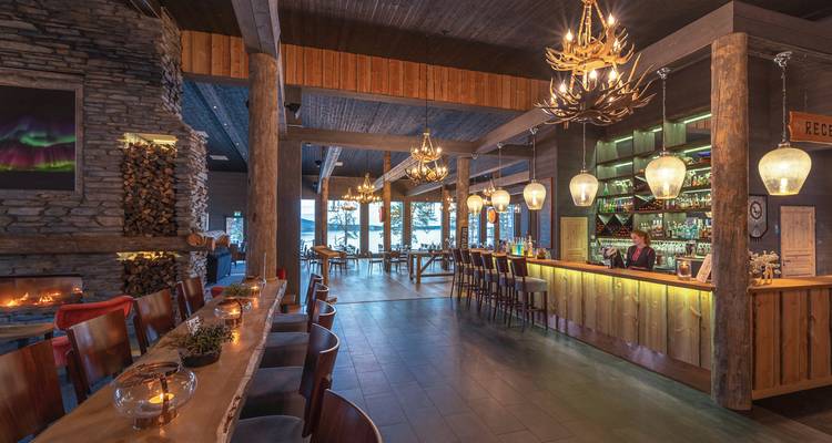 A cozy bar and restaurant with warm lighting and a view of a lake.