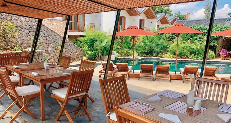 Zona de comedor al aire libre con piscina y tumbonas.