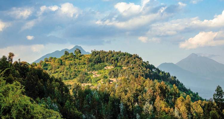 Malerische Aussicht auf Hügel und Wälder mit vereinzelten Unterkünften in der Ferne.