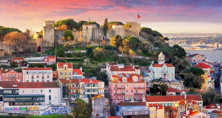 Panoramic sunset over Lisbon with São Jorge Castle atop the hill and colorful houses below