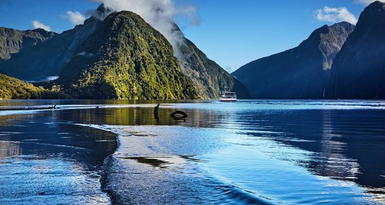 Bateau naviguant dans un fjord serein avec des montagnes.