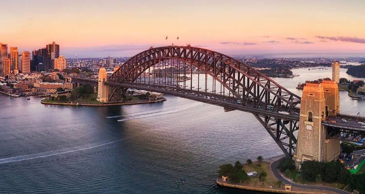 Pont célèbre enjambant un port au coucher du soleil.
