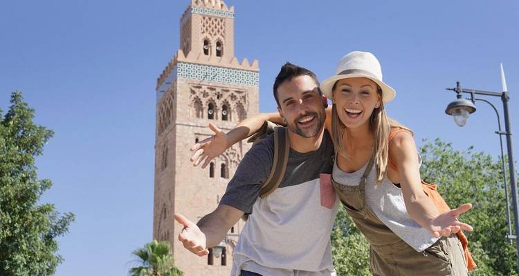 Un couple posant devant un bâtiment historique avec un minaret élancé.