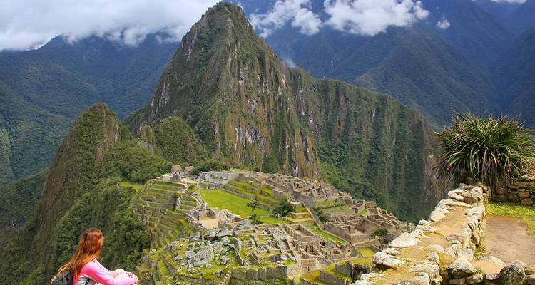 Eine Person, die die antiken Ruinen von Machu Picchu mit Bergen im Hintergrund überblickt.