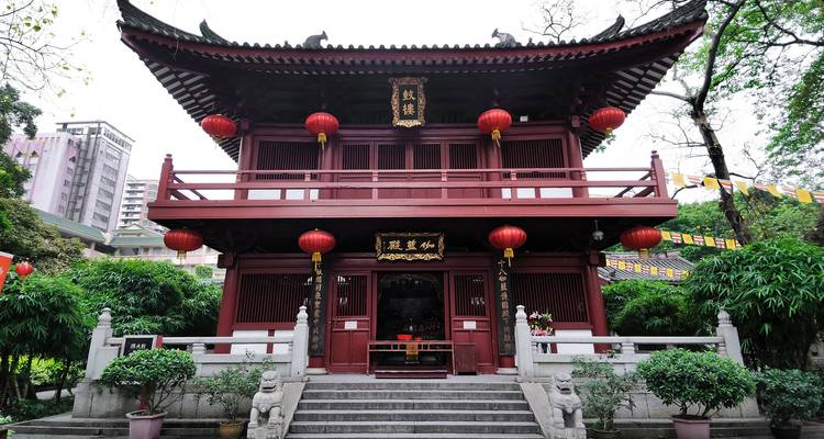 Traditional Chinese building with red lanterns surrounded by greenery.