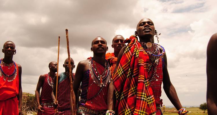 Groupe d'hommes masaïs marchant en file, vêtus de vêtements traditionnels.