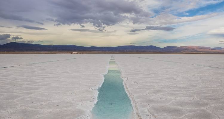 Uitgestrekte zoutvlaktes onder een bewolkte hemel.