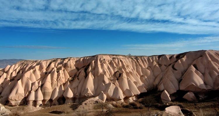Eroded pink cliffs and ridges under patterned clouds in Cappadocia
