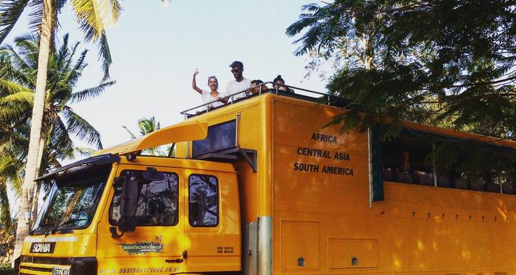 Groep bovenop een gele safaritruck die zwaait