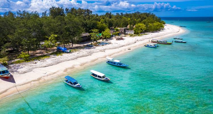 Boote reihen sich in der Nähe eines unberührten Strandes mit klarem türkisfarbenem Wasser auf.