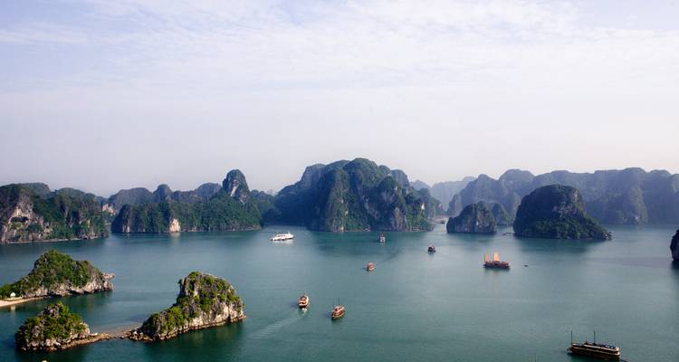 Emerald green bay dotted with limestone karst islands and boats