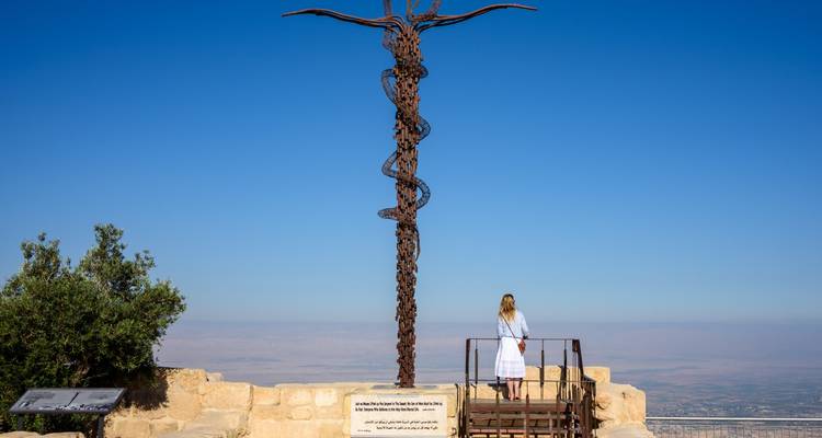 Person standing next to a tall sculpture with a view.