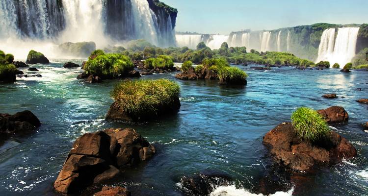 Expansive view of Iguazu Falls with rocks and vegetation.