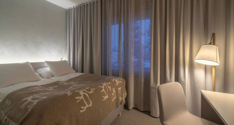 Une chambre d'hôtel faiblement éclairée avec les rideaux tirés.