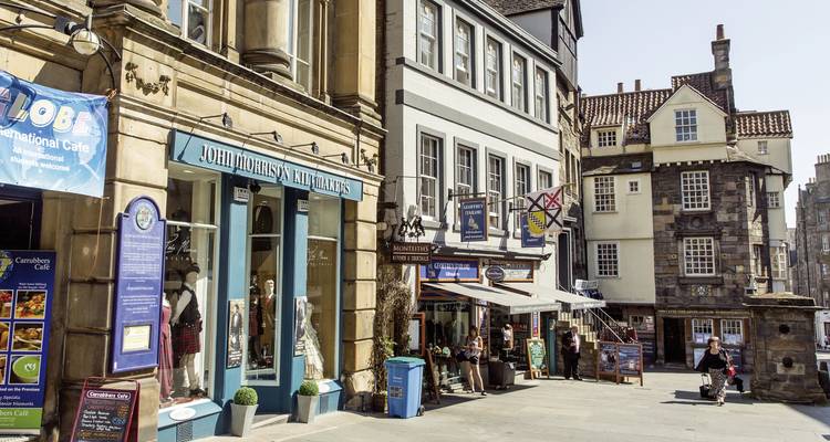 Una pequeña calle con tiendas y letreros.