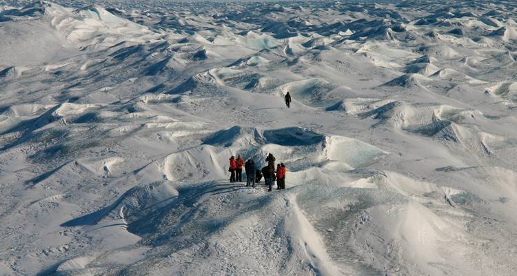 People hiking on an ice field with textured snow formations.