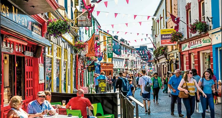 Scène de rue animée avec des cafés et des piétons.