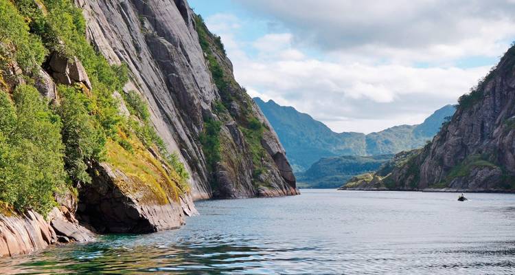 Narrow fjord with steep cliffs and lush vegetation.