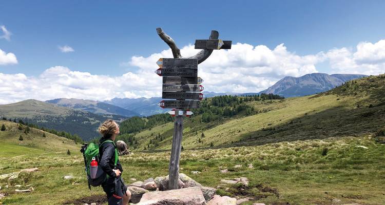 Hiker standing by a signpost with mountain view.