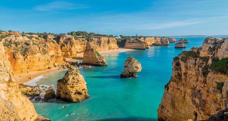 Klippen und Felsformationen entlang eines türkisfarbenen Meeres.