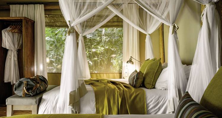 Luxuriöses Lodge-Schlafzimmer mit Himmelbett und Waldblick.