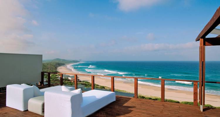 Vue imprenable sur l'océan depuis une terrasse en bois par une journée ensoleillée.