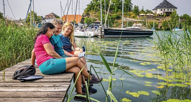 Groupe assis au bord d'un lac avec des bateaux en arrière-plan.
