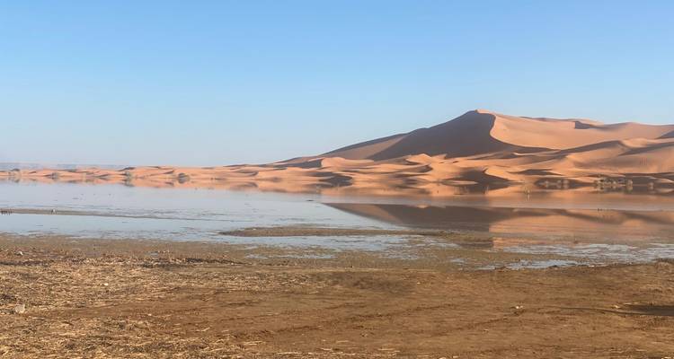 Paisaje desértico con dunas de arena reflejadas en un cuerpo de agua.