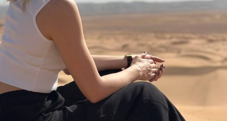 Primer plano de una persona sentada en una duna del desierto.