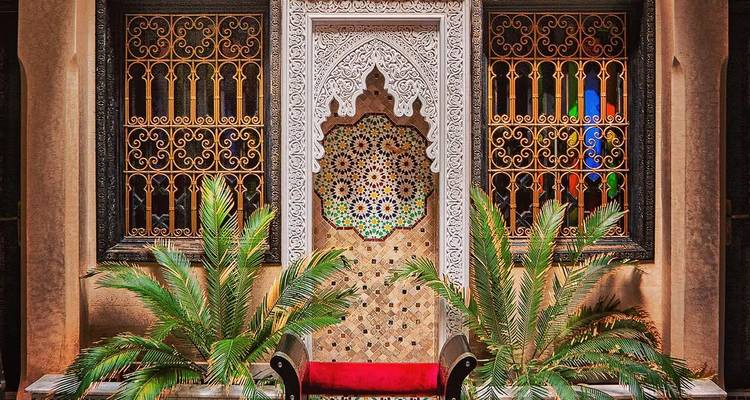 Interior marroquí ornamentado con patrones intrincados y plantas exuberantes.