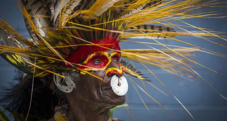 Eine Person in traditioneller Kleidung mit Gesichtsbemalung und Kopfschmuck.