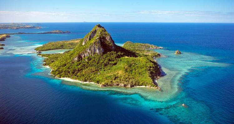 Luftaufnahme einer Insel mit üppigem Grün und blauem Wasser.