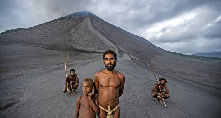 Menschen in traditioneller Kleidung stehen in der Nähe einer vulkanischen Umgebung.