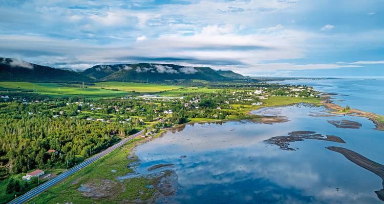 Coastal landscape with a small settlement and mountains.