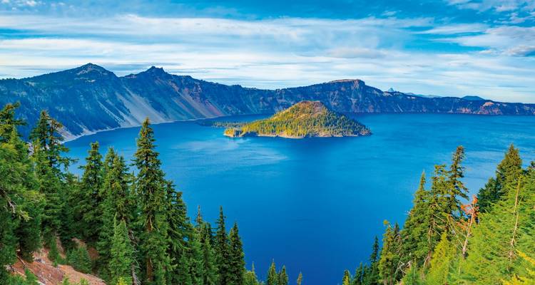 Crater lake with deep blue water surrounded by cliffs and forests.