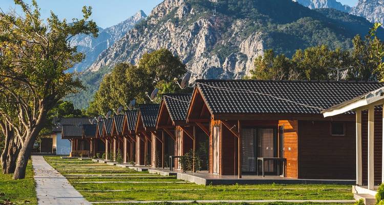 Rij houten hutten met bergen op de achtergrond.