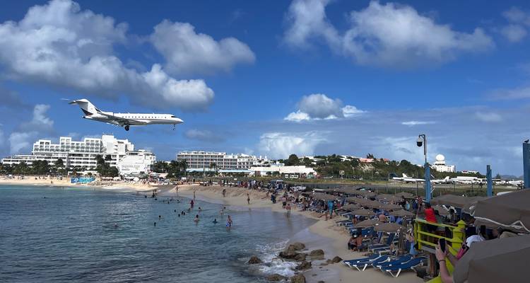 Airplane flying low above a crowded beach.