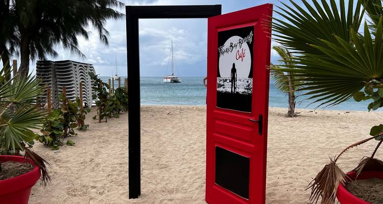 Open door on a beach with boats in the distance.