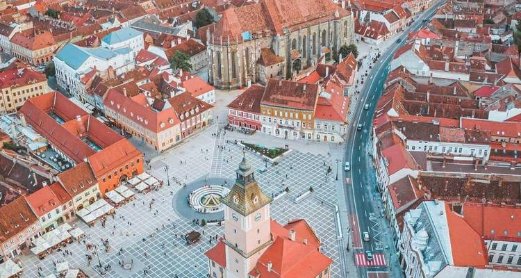 Luftaufnahme einer historischen Stadt mit roten Dächern und zentralem Platz.