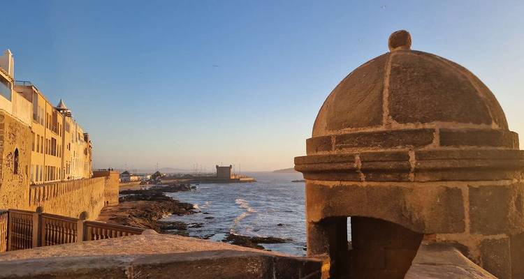 Stone fortification overlooking the sea at sunset.